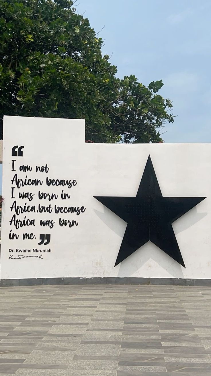 A white wall with a large black star and a quote from Dr. Kwame Nkrumah painted on it